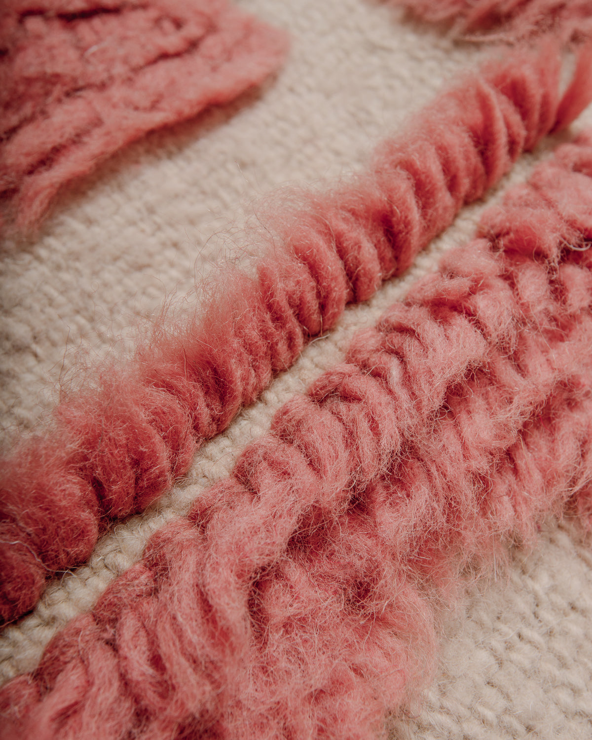 Detail of Berberlin Special Edition Beniourain rug with textural design made up of fluffy knotted wool pile in a soft dusty rose colour and flat woven base in natural cream.